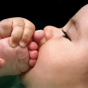 bebê colocando o pé na boca